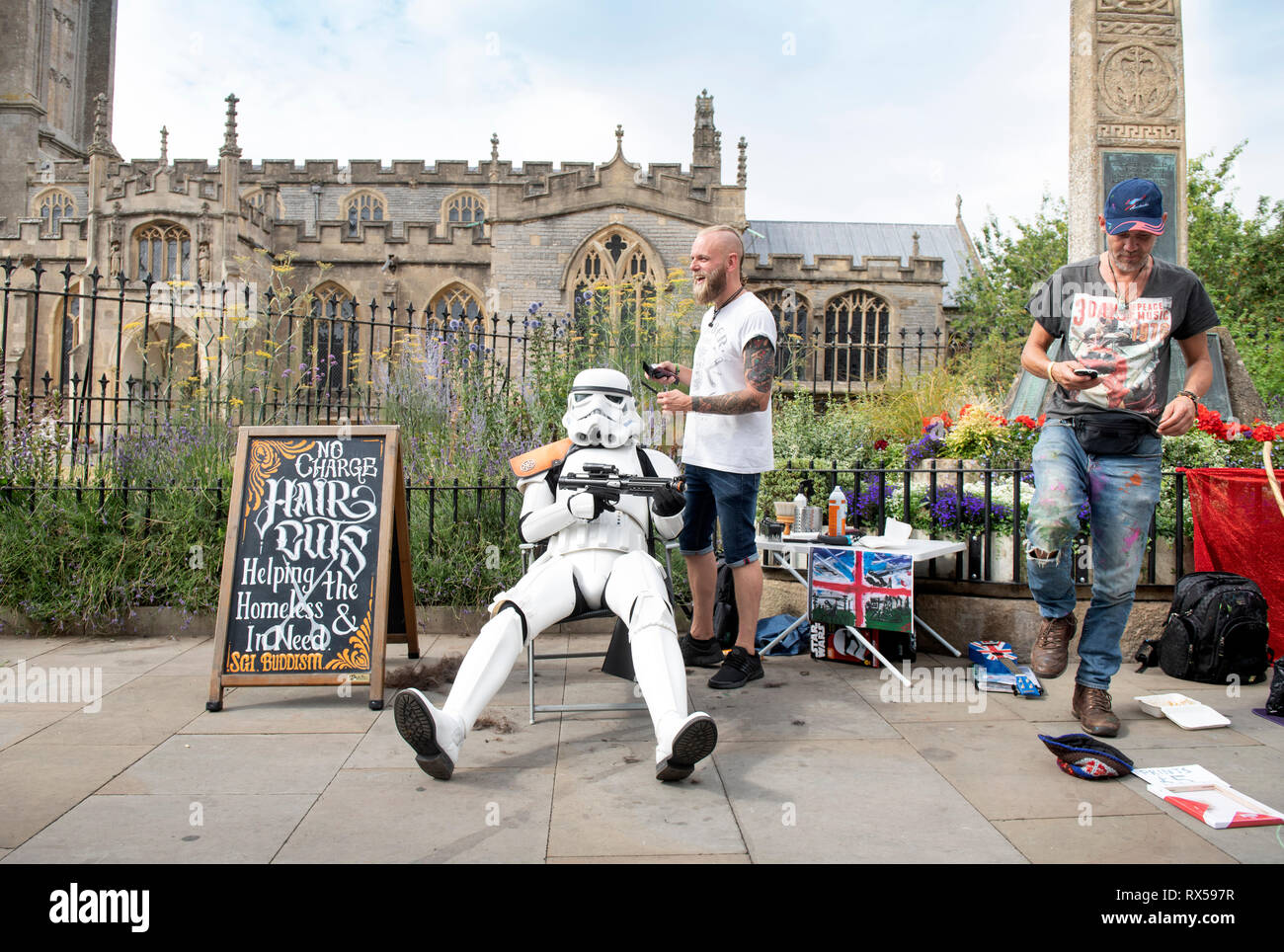 Ein Bewohner gekleidet wie ein Stormtrooper aus Star Wars mit der Straße Friseur bietet kostenlose Haarschnitte für Obdachlose in der High Street, Glastonbury, Großbritannien Stockfoto