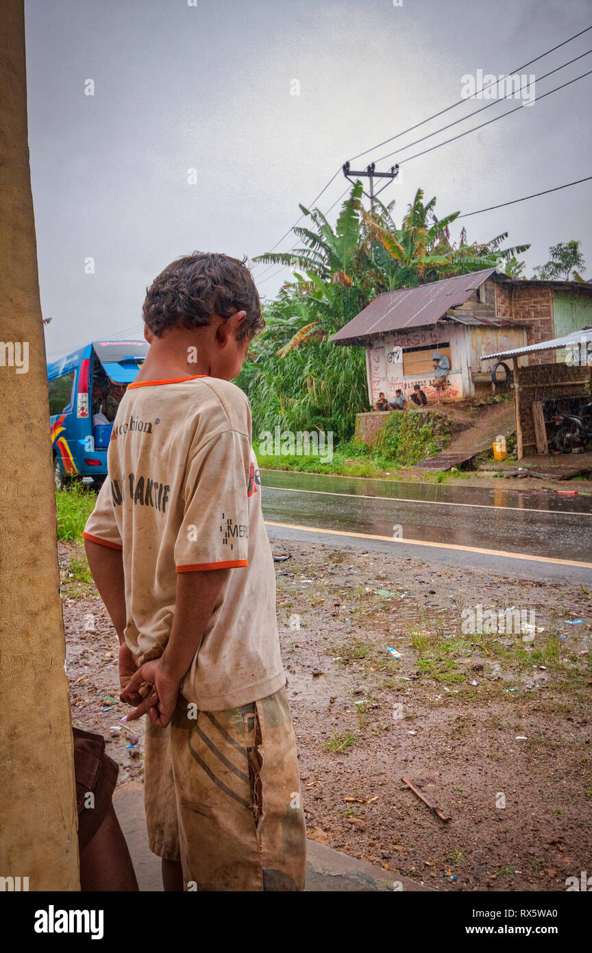 Asiatische kid warten auf den Regen zu stoppen. Flores ist eine der Kleine Sunda Inseln, einer Inselgruppe in der östlichen Hälfte von Indonesien. Stockfoto