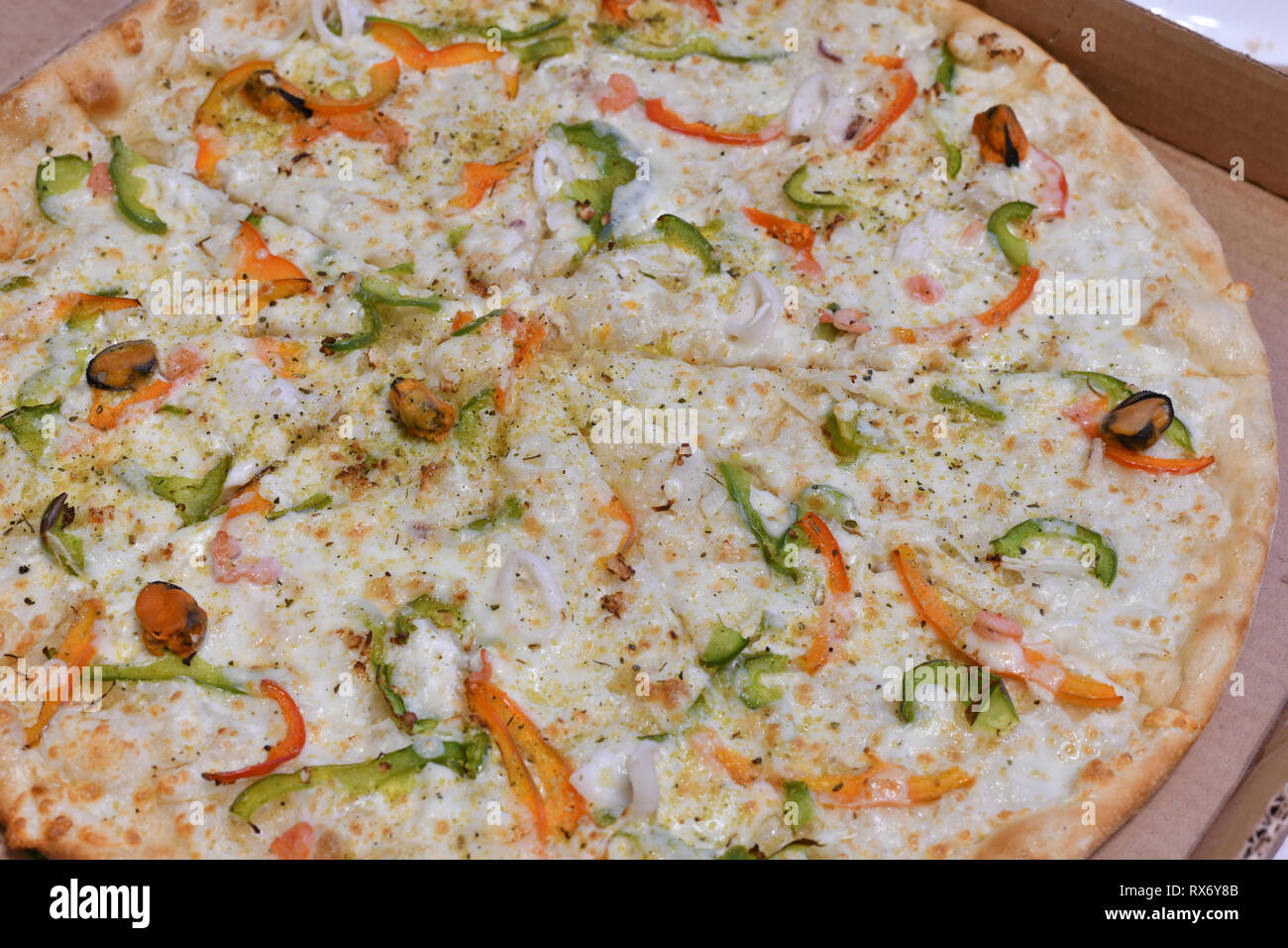 Pizza mit Meeresfrüchten und Gemüse im Karton Stockfoto