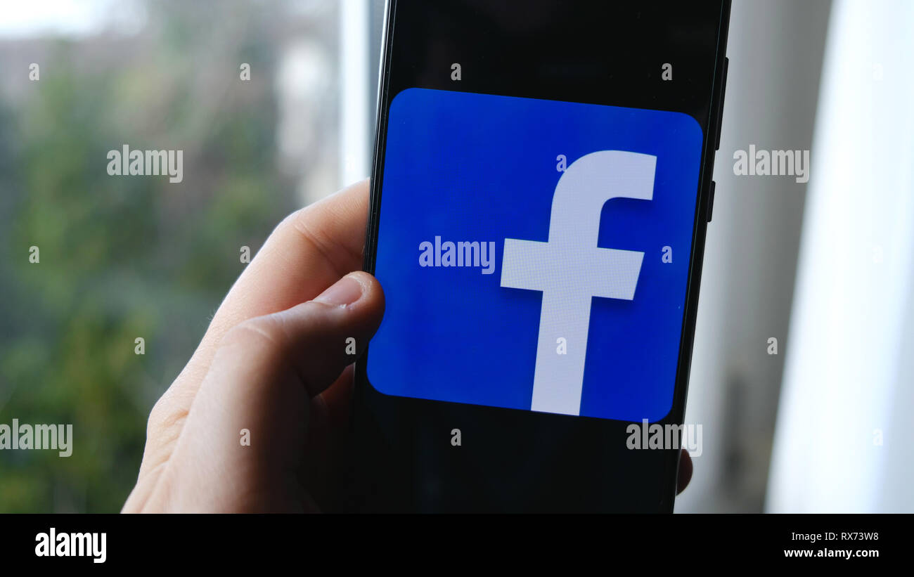 Hand und Finger verwenden Facebook App Symbol auf einem Smartphone Stockfoto