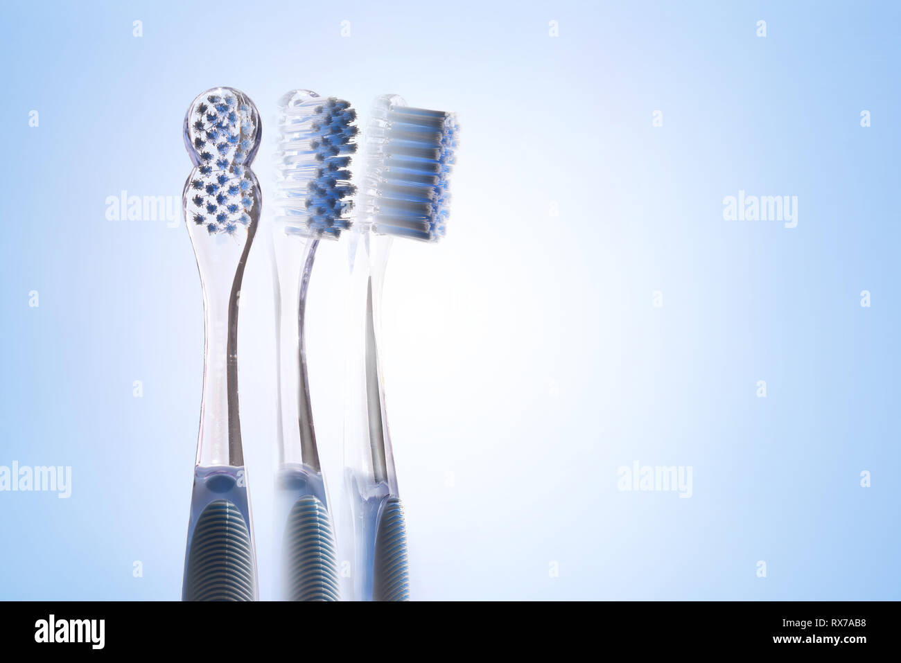 Drei Ansichten von transparent blau Zahnbürste auf blauen Gradienten Hintergrund. Horizontale Komposition. Stockfoto