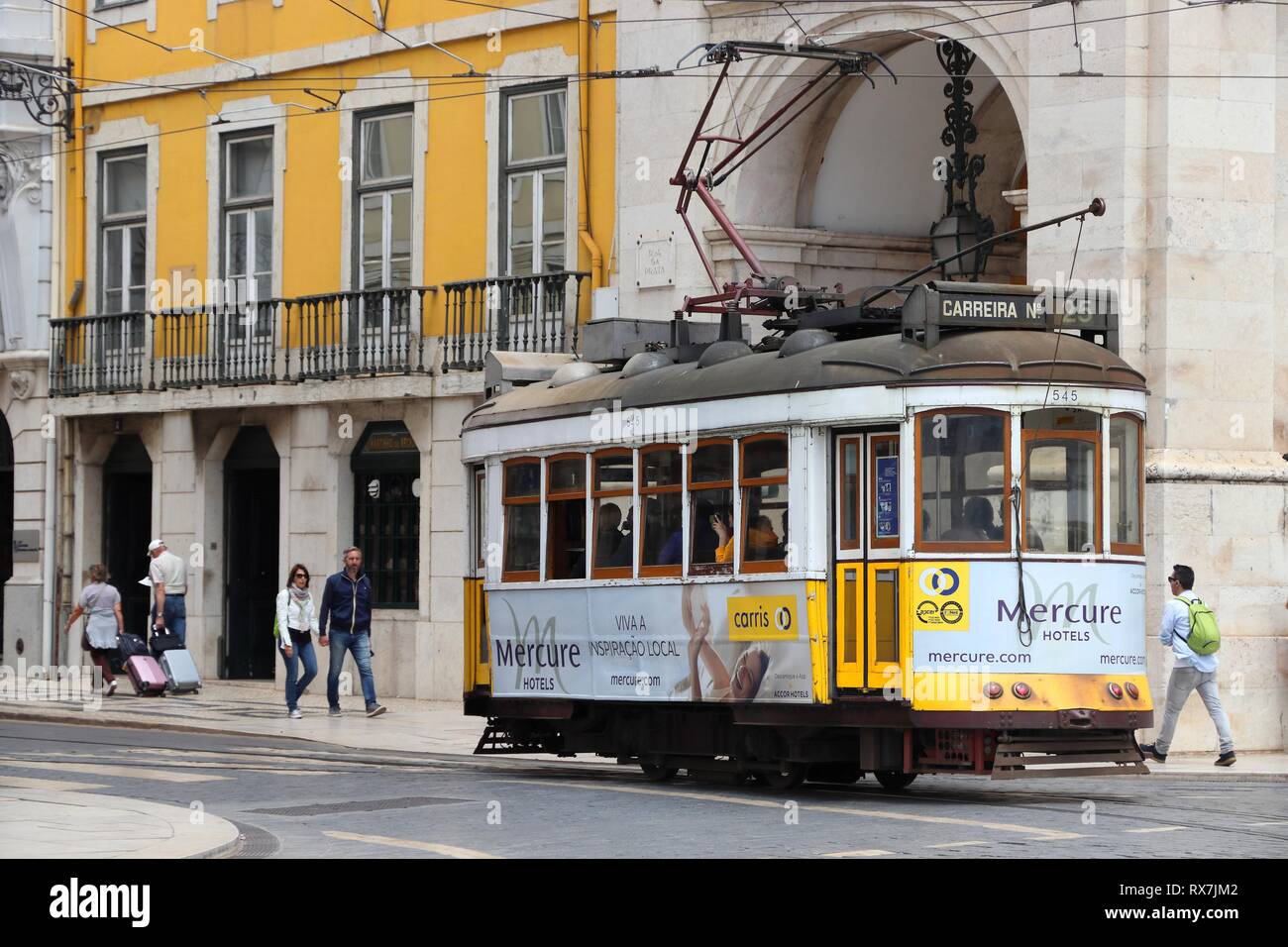 Lissabon, Portugal - Juni 4, 2018: die Menschen fahren Sie mit dem gelben Straßenbahn in Praca Comercio Platz in Lissabon, Portugal. Der Lissaboner Straßenbahn stammt aus dem Jahre 1873 mit einem Stockfoto