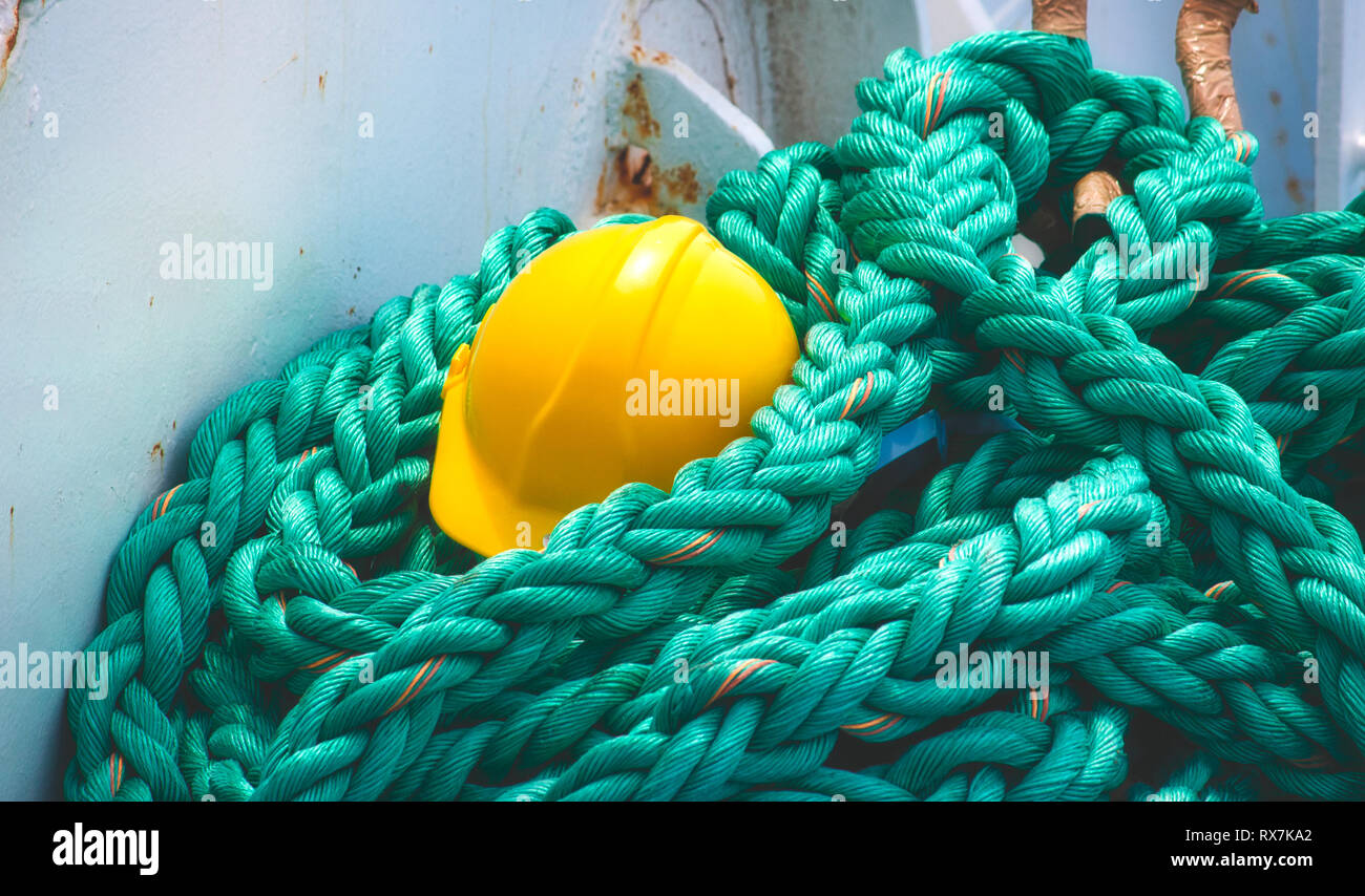 Gelbe harten Hut auf Lügen gewellt heavy duty Seil an Bord eines Schiffes mit Meerblick Stockfoto