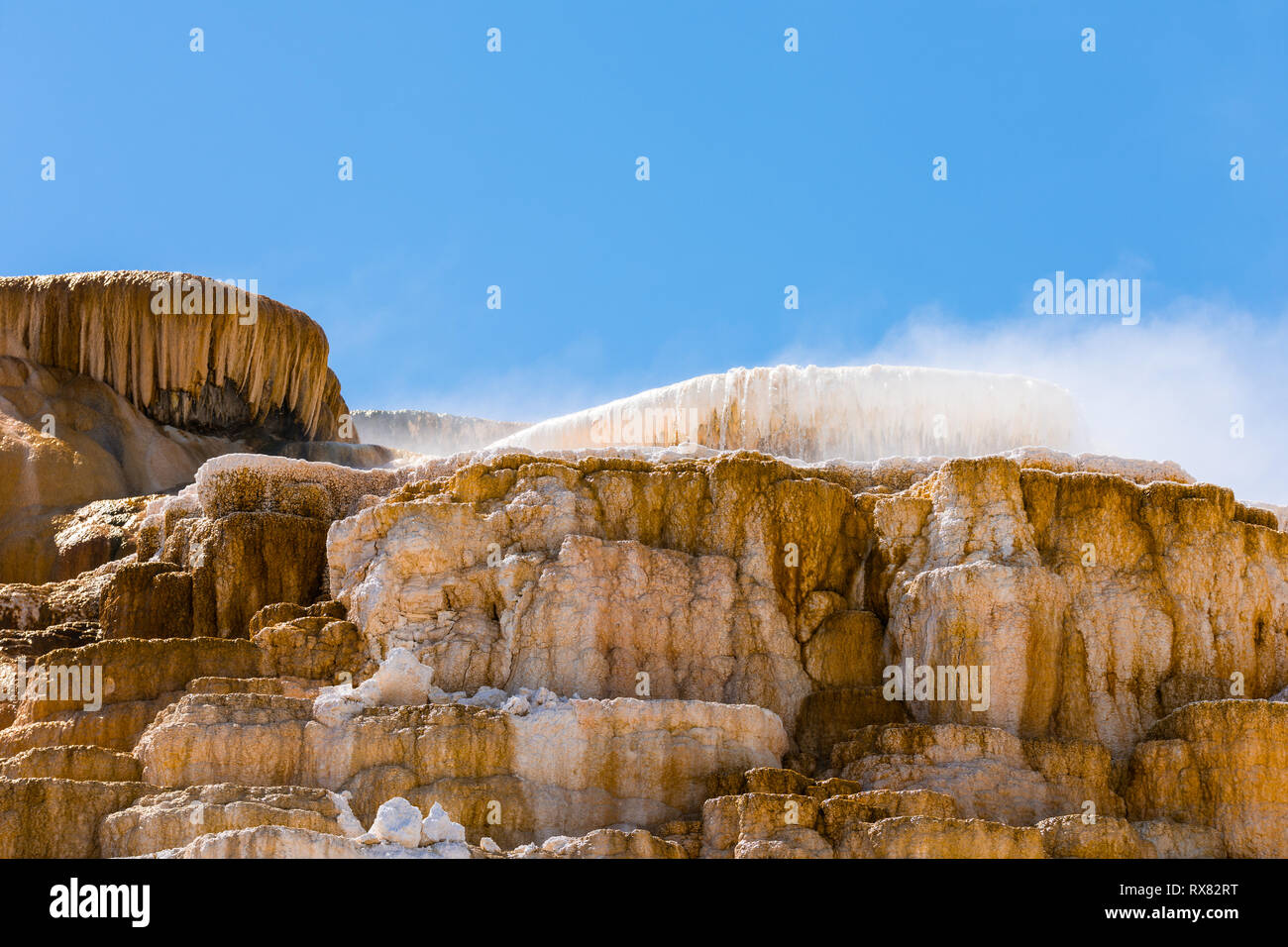 Wasserfall über Orange und Weiß mineralische Ablagerungen im Yellowstone National Park Stockfoto