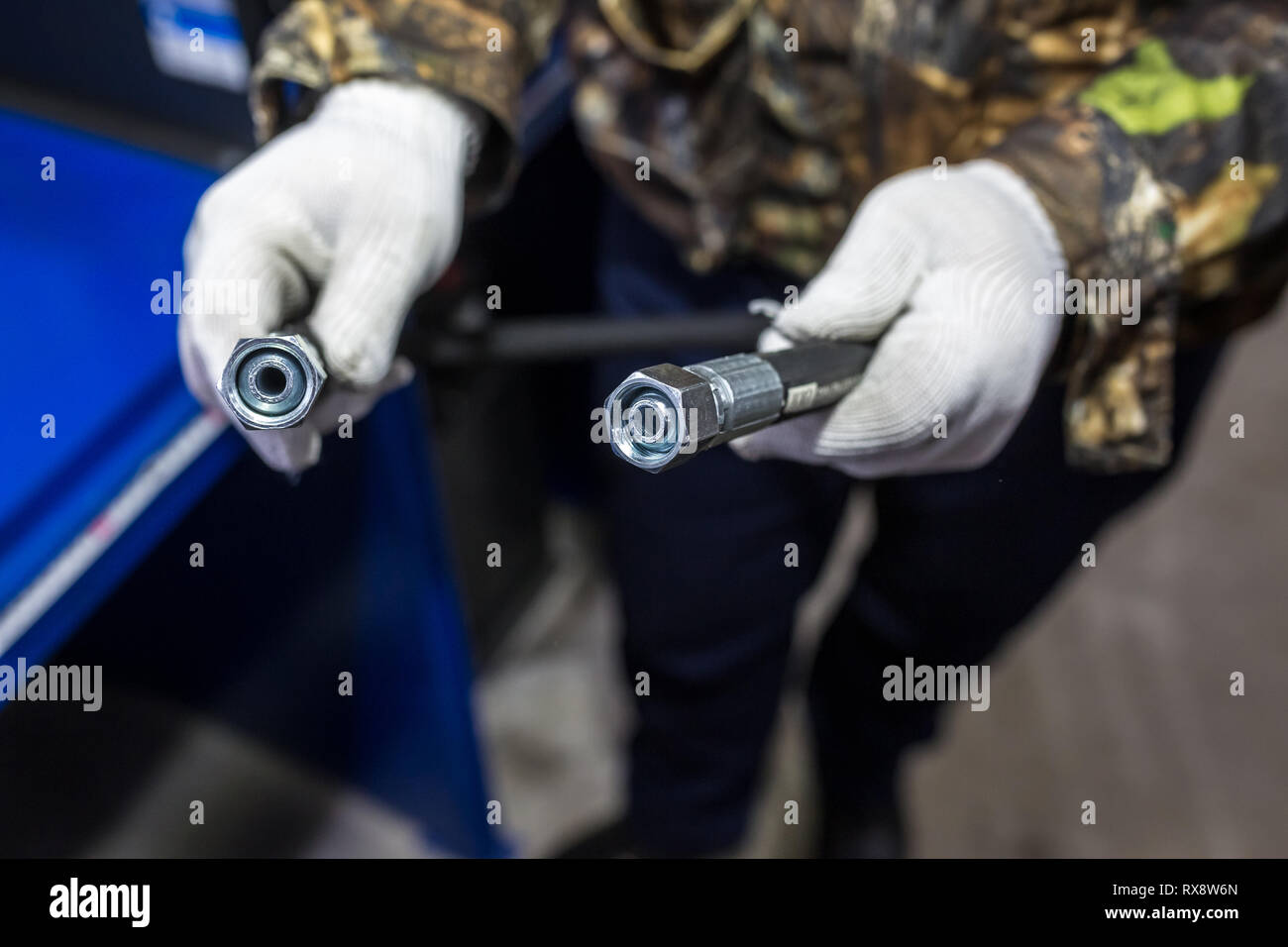 Der Mensch ist mit einem Hochdruckschlauch mit Fittings Stockfoto