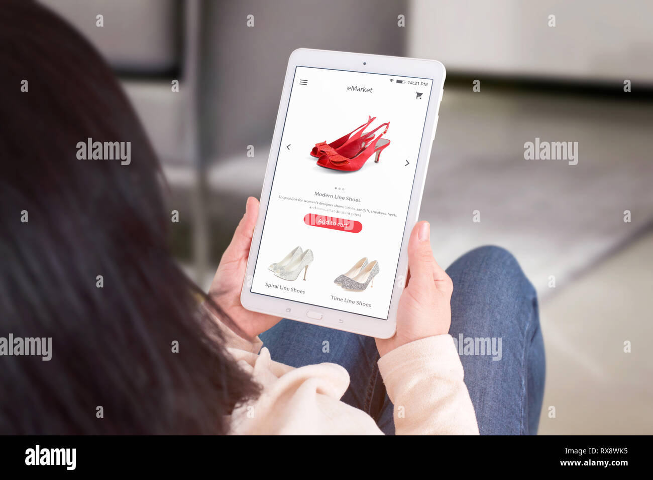 Online shopping aus dem Stuhl mit Tablet. Blick über die Schulter. Wohnzimmer im Innenbereich im Hintergrund. Stockfoto