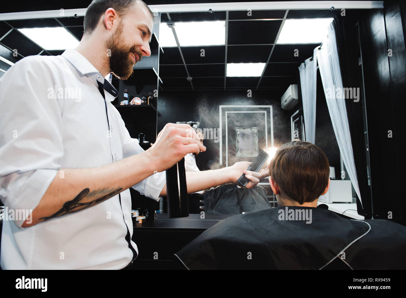 Junge schöne Friseur die Haare schneiden von süßen Jungen im barbershop. Stockfoto