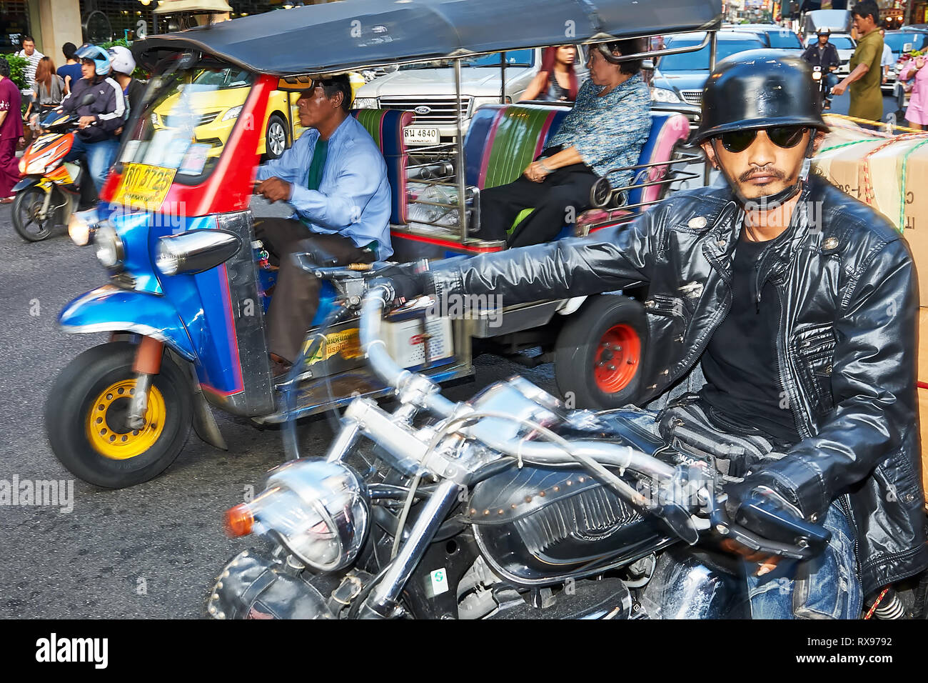 Bangkok, Thailand: Nahaufnahme einer bunten Tuk-Tuk Fahrzeug mit einem Pkw und einem Motorradfahrer in schwarzes Leder gekleidet Stockfoto