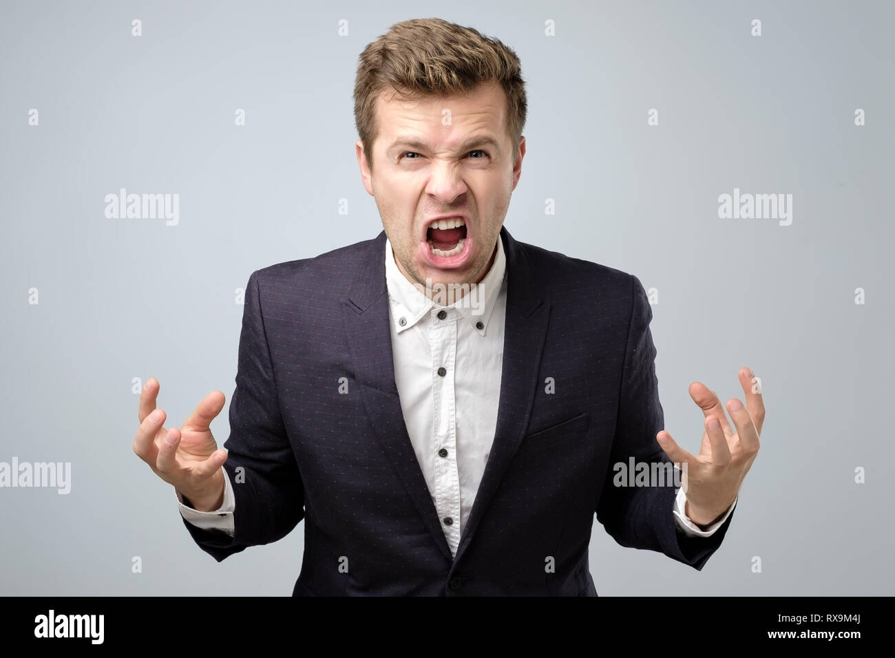 Zorn verrückt stattlicher Mann in Anzug ständigen rufen oder Schreien. indoor Studio gedreht. Stockfoto