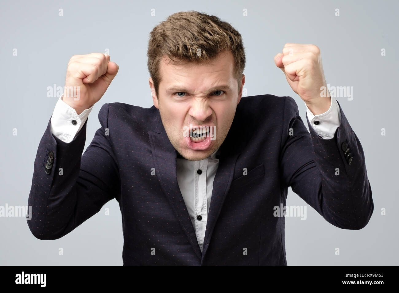Zorn verrückt stattlicher Mann in Anzug ständigen rufen oder Schreien. indoor Studio gedreht. Stockfoto