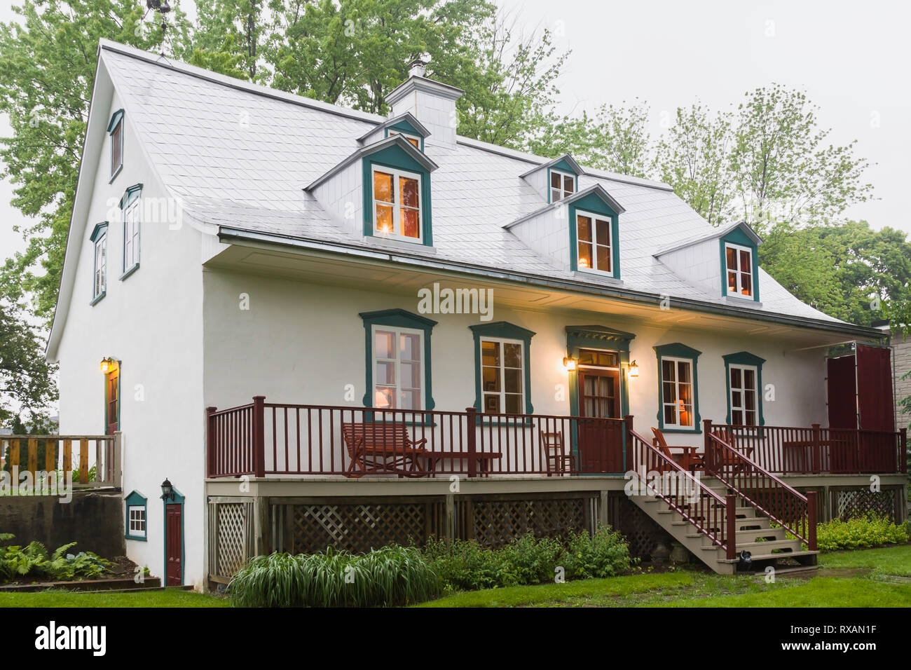 Rückansicht des beleuchteten alten, ca. 1805 weißen Raufusses mit burgunderroten und grünen Zierstreifen im kanadischen Cottage-Stil Haus im späten Frühling, Quebec, Kanada. Dieses Bild ist Eigentum freigegeben. CUPR0323 Stockfoto