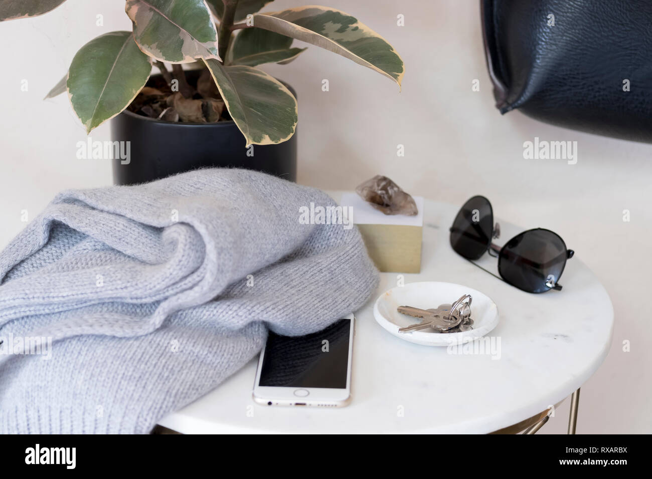 Hohe Betrachtungswinkel von persönlichen Accessoires mit Pflanzen- und Buch auf dem Tisch gegen die Wand zu Hause Stockfoto