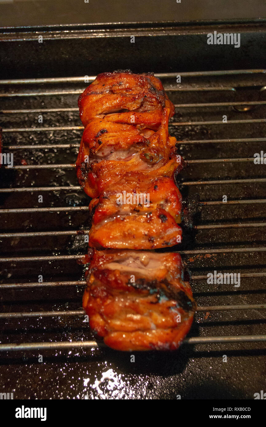 Eine Nahaufnahme der gekochten Stücke Huhn zusammen auf einem Holz Stick oder Kebab auf dem Backblech Abkühlen beofre surved für Abendessen, Stockfoto