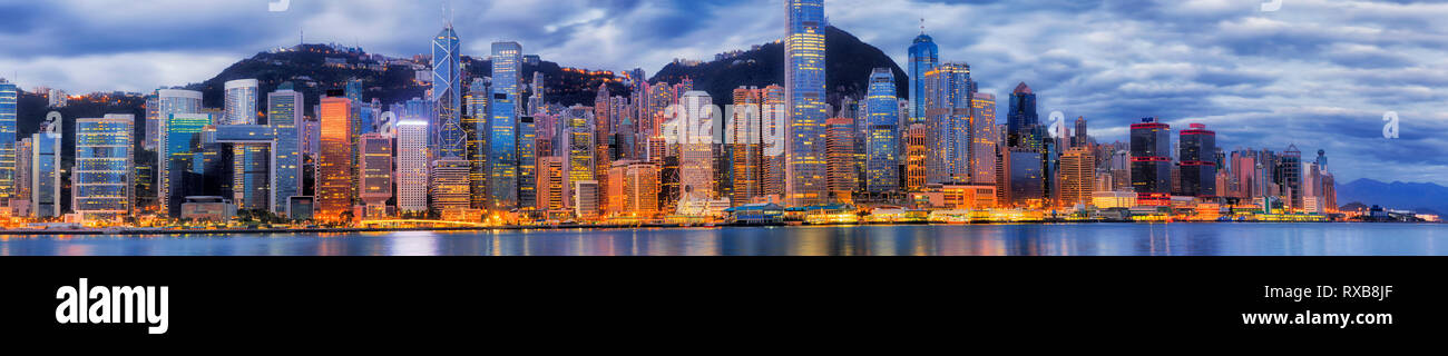 Central District von Hong Kong City CBD am Ufer des Victoria Harbour gegen Bergkette mit helle Beleuchtung bei Sonnenaufgang - breite Stadtbild p Stockfoto