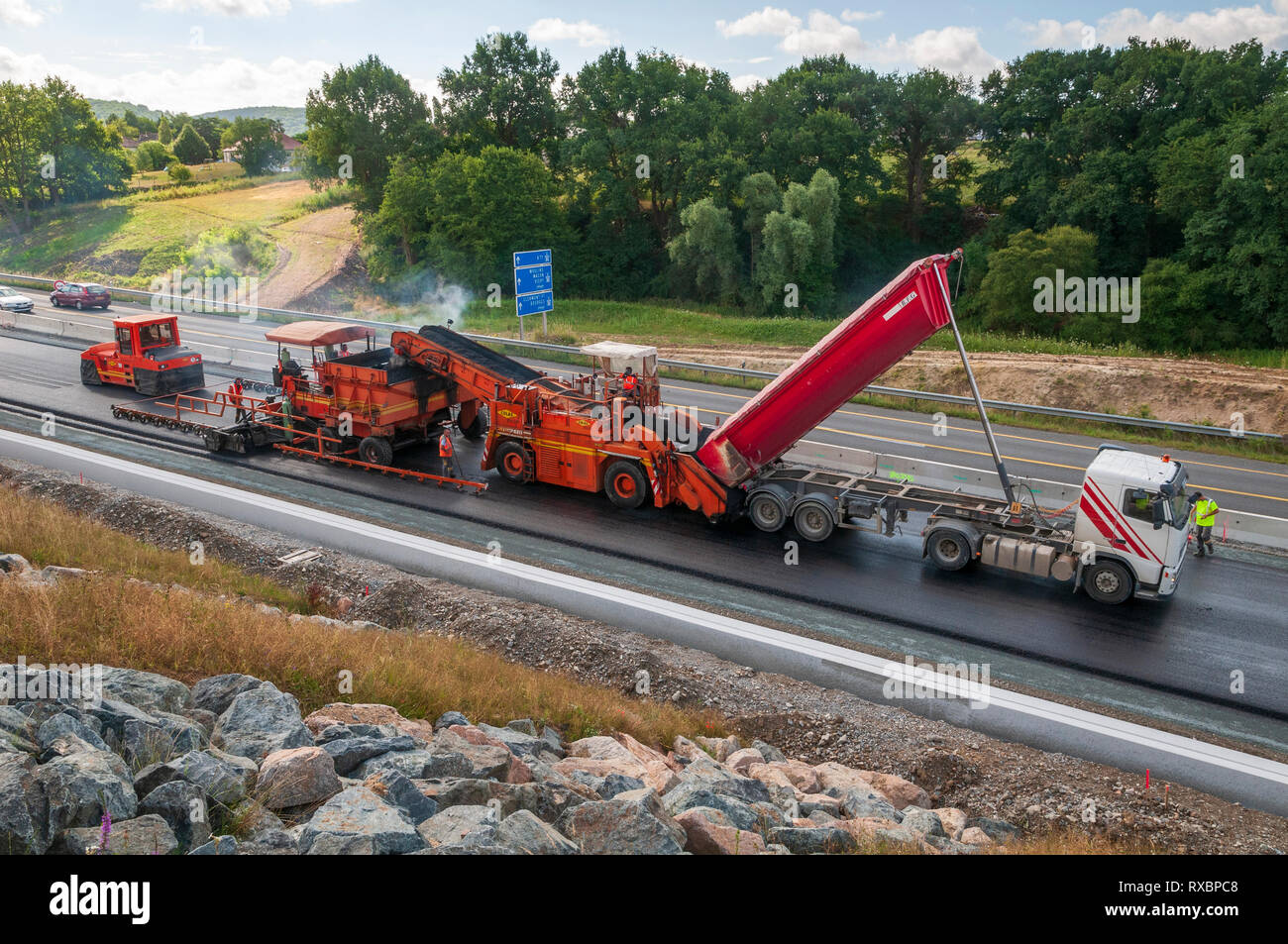 Asphalt Anwendung auf einer Schnellstraße. Alle Geräte in Aktion asphalt Lkw, transfer vehicle, Finisher und Walzen. Stockfoto