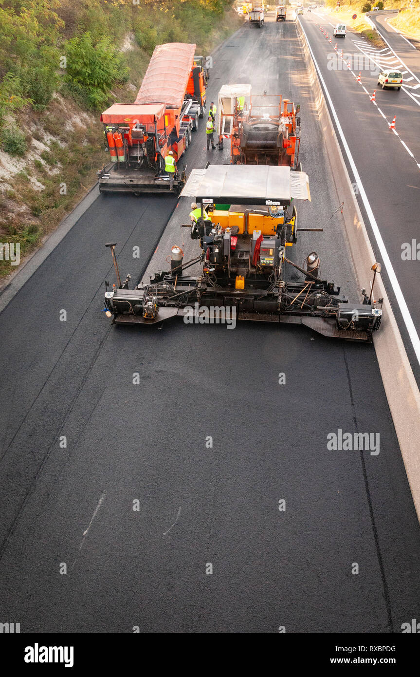 Asphalt Anwendung auf einer Schnellstraße. Alle Geräte in Aktion asphalt Lkw, transfer vehicle, Straßenfertiger. nach oben Blick auf die Bohle Stockfoto