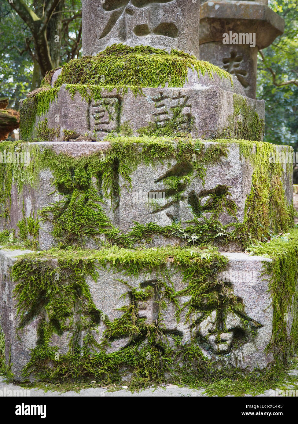 Nara, Japan - 15 Okt 2018: verwitterte Japanische Zeichen auf einem alten moosbewachsenen Stein Struktur in der Nähe des Kasuga Grand Schrein von Nara, Japan. Stockfoto