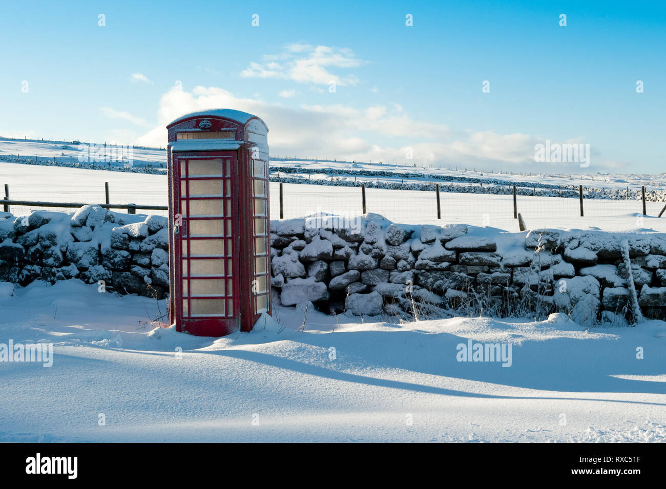 Traditionelles rotes BT Telefonzelle in ländlicher Lage auf einem winterlichen, verschneiten Tag Stockfoto