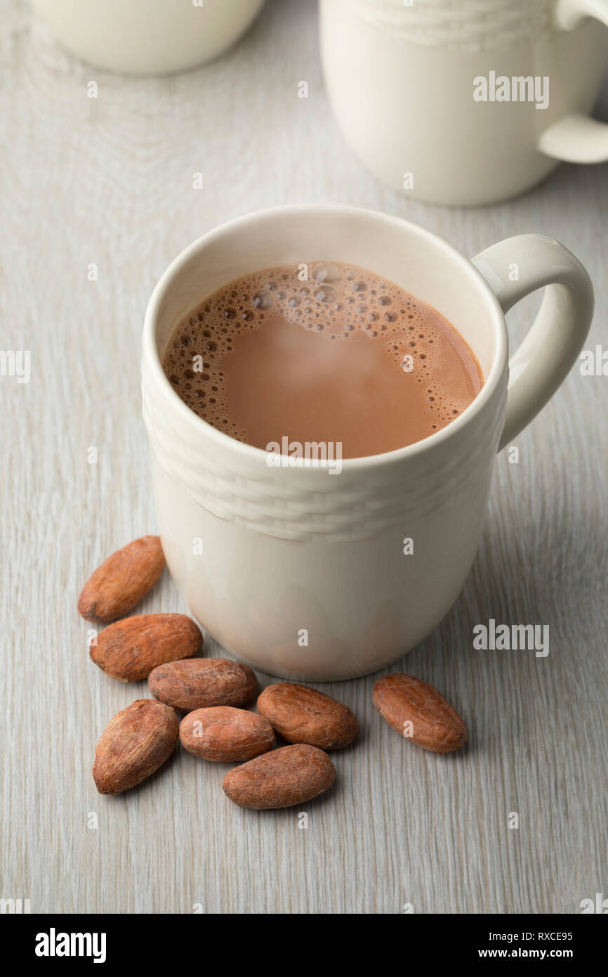 Becher mit heißer Schokolade Milch und ganze Kakaobohnen Stockfoto