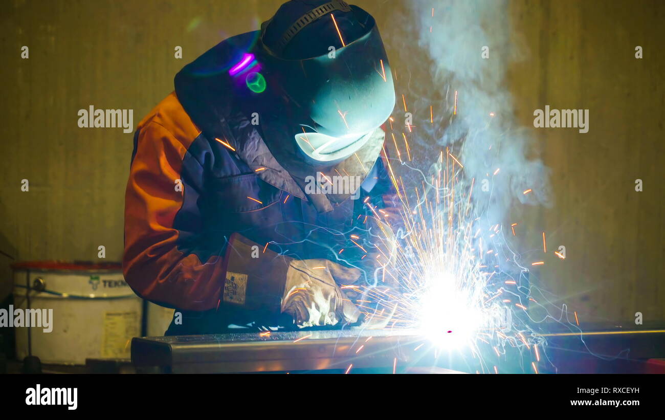 Ein Schweißgerät arbeiten an der Metalle und Rohre in der Fabrik. Ein schweisser Schweißer oder Bediener ist ein Tradesperson, die beim Schweißen Materialien spezialisiert hat. Stockfoto
