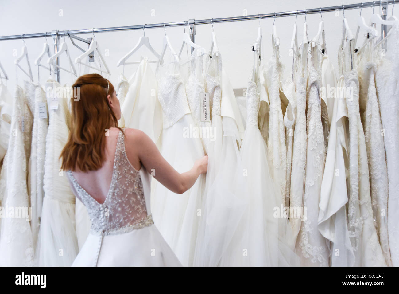 Eine hübsche rothaarige Mädchen ist Hochzeit Kleid einkaufen, indem sie sich in einen schönen Shop - sie versucht auf Kleider und Schuhe Stockfoto