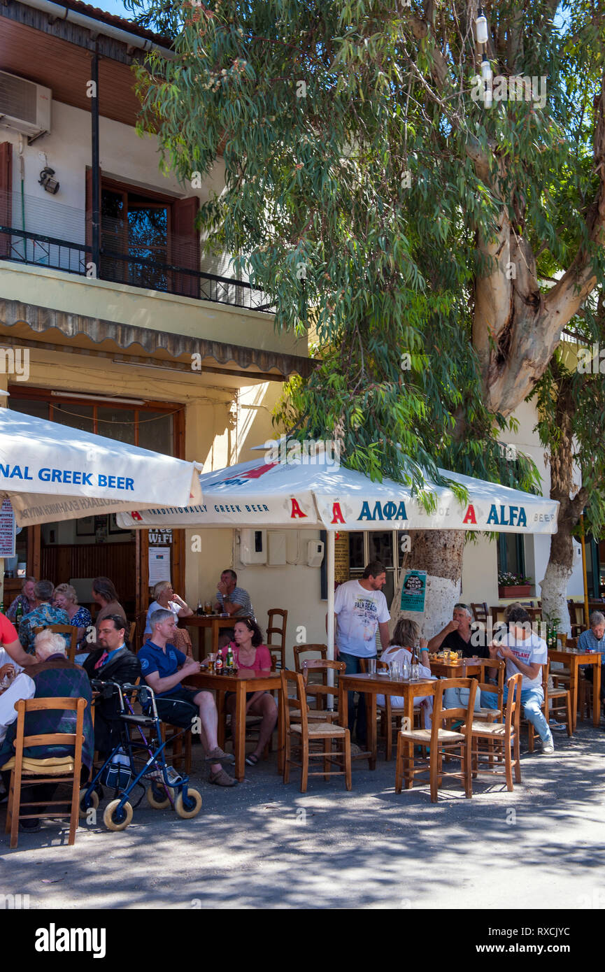 Menschen auf einer Terrasse im Freien, eine Taverne am Hauptplatz des Dorfes von Vamos auf der griechischen Insel Kreta. Stockfoto