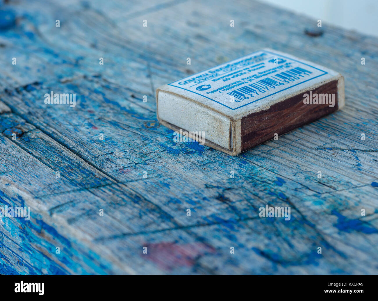 Eine alte Licht Schachtel Streichhölzer liegt auf einem abgenutzten Blau Bank. Stockfoto