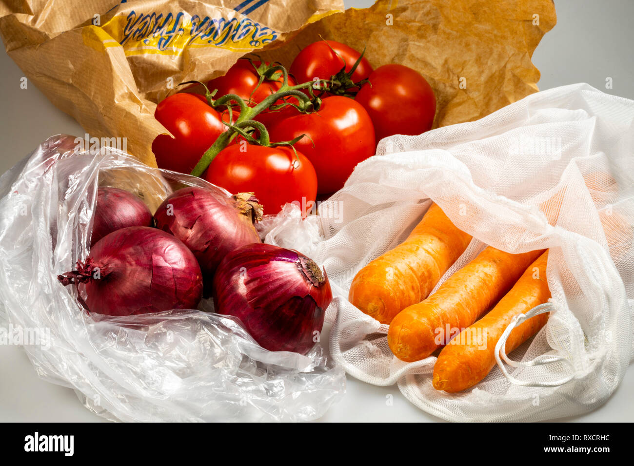 Verpackungen für Lebensmittel, Karotten in einer wiederverwendbaren Kunststoff net, Vermeidung von plastik Müll, Zwiebeln in eine wiederverwendbare Tasche, Tomaten in einer Papiertüte, Stockfoto