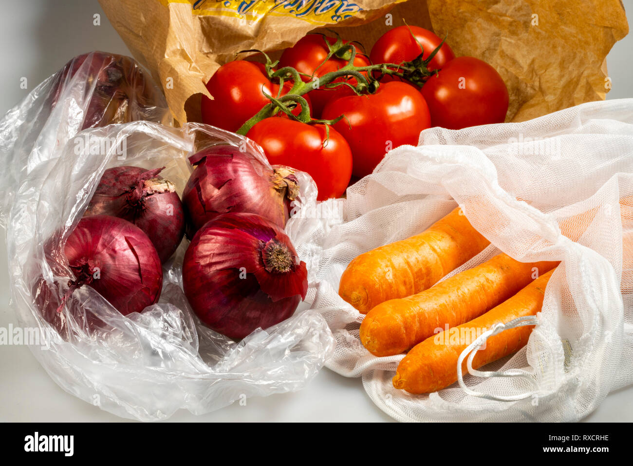 Verpackungen für Lebensmittel, Karotten in einer wiederverwendbaren Kunststoff net, Vermeidung von plastik Müll, Zwiebeln in eine wiederverwendbare Tasche, Tomaten in einer Papiertüte, Stockfoto