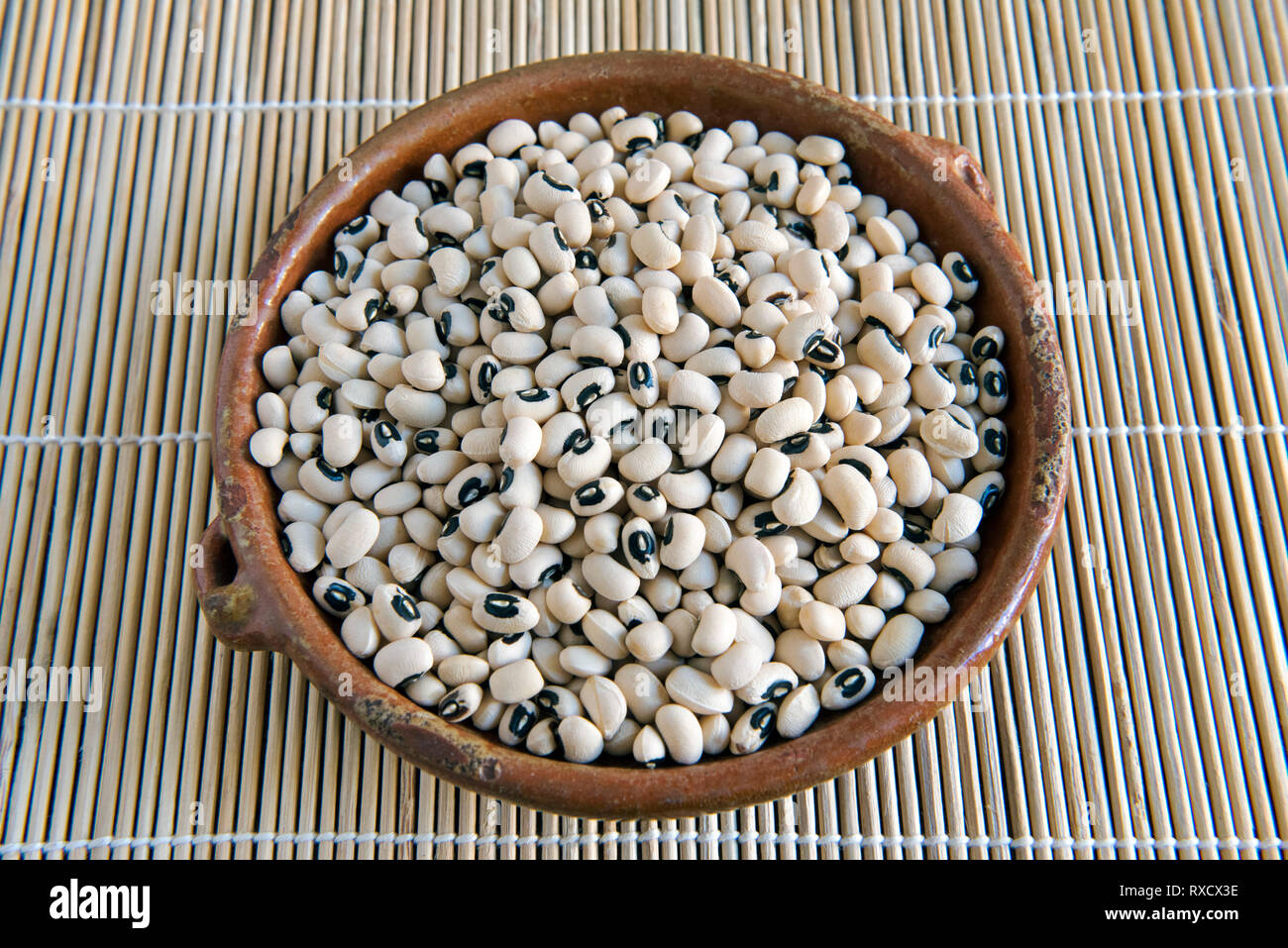Black Eyed Beans in Distressed vintage Gericht auf Tischset. Stockfoto