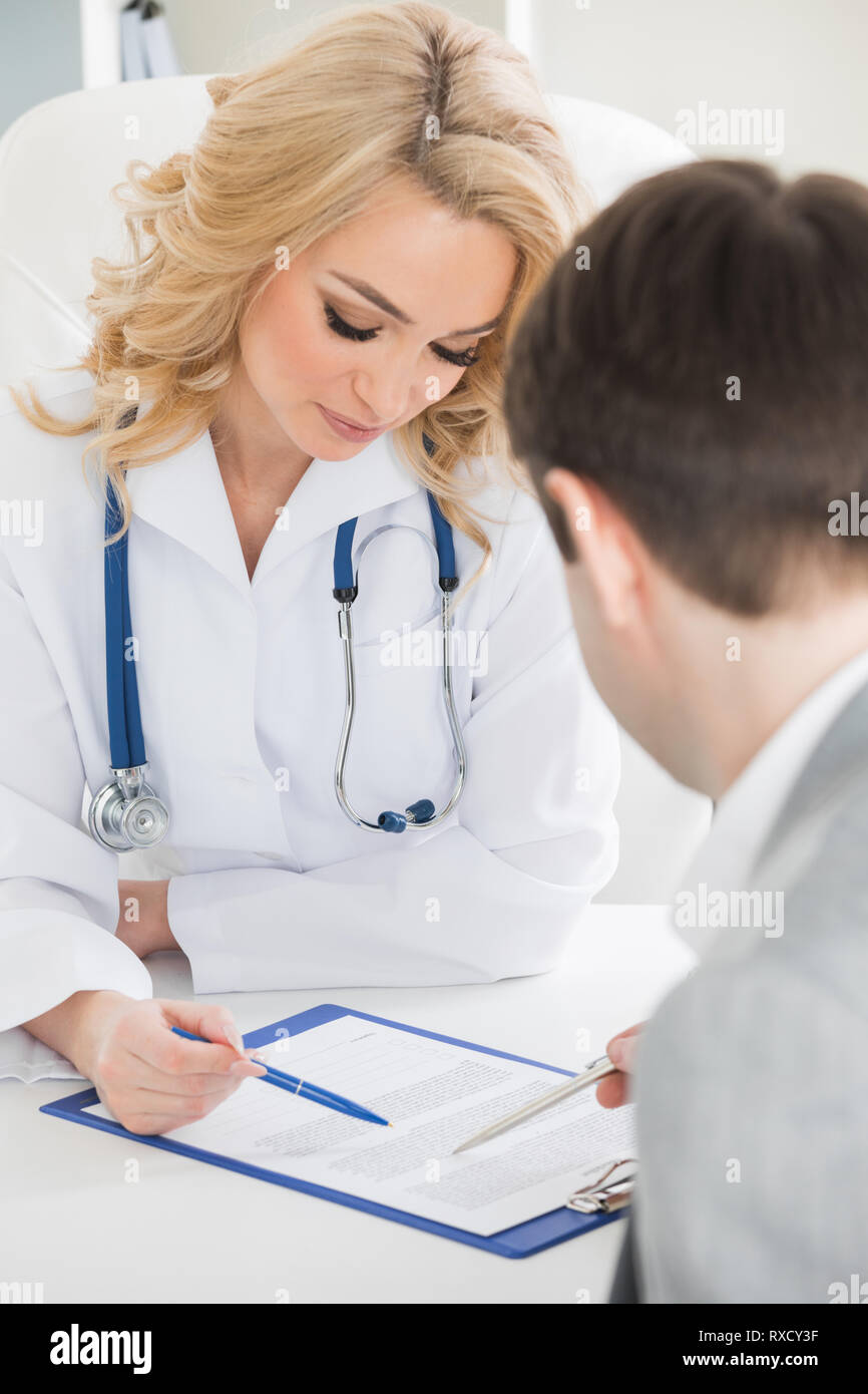 Arzt mit dem Patienten ein Vertrag Dokument in klinischen Büro Stockfoto