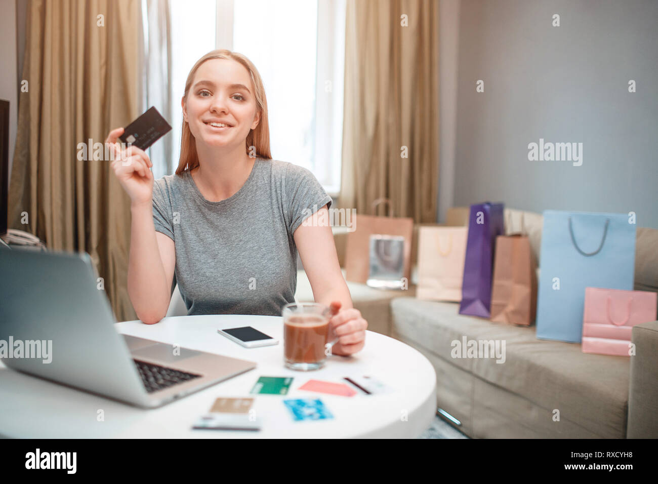 Online Shopping zu Hause. Junge Frau bereit ist, Geld von Payment Card am schwarzen Freitag zu verbringen, während am Tisch sitzen Stockfoto