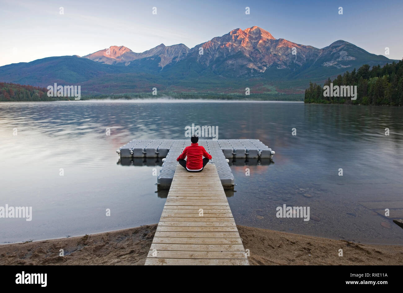 Mann auf dem Dock meditieren im Pyramid Lake, Jasper National Park, Alberta, Kanada. Stockfoto