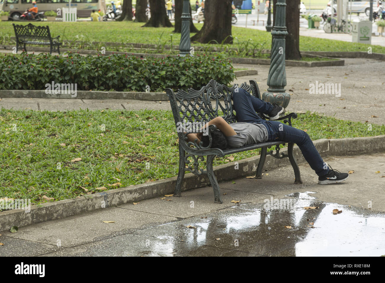 Man Rest an Bank an der Straße in Ho Chi Minh, Vietnam Stockfoto