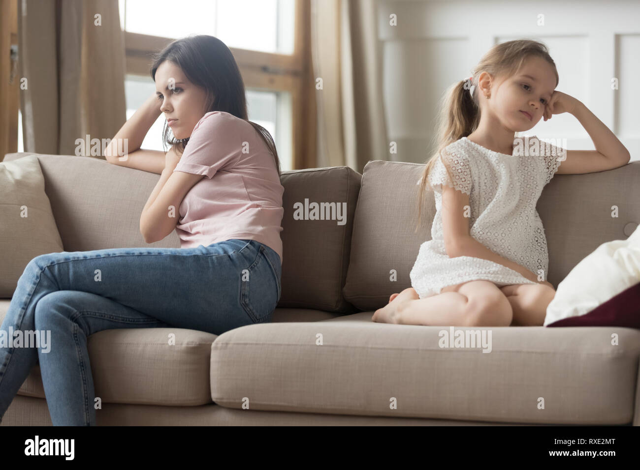 Hartnäckige Mutter und Kind Mädchen wandte sich Sitzen auf einem Sofa Stockfoto