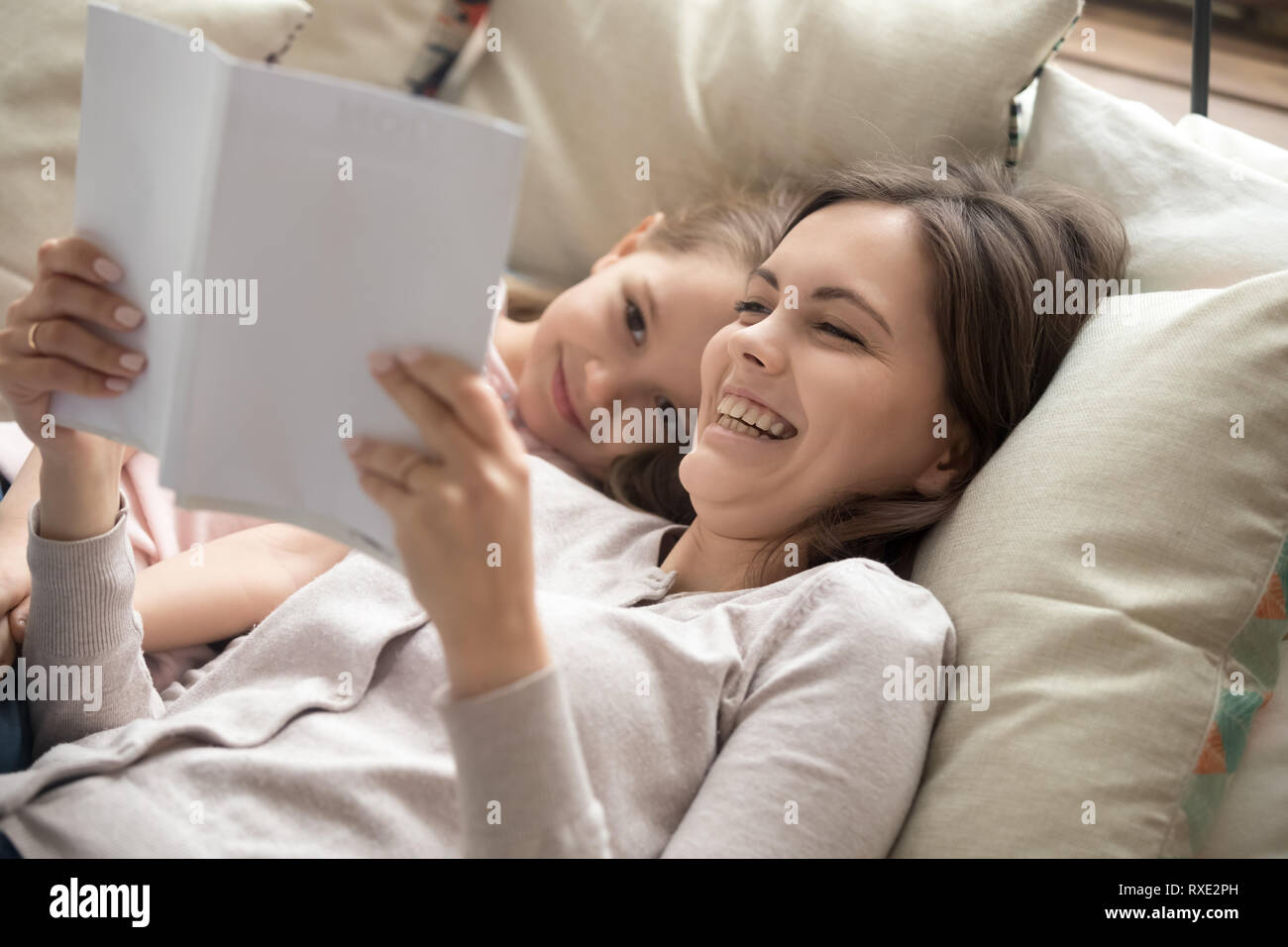 Glückliche Mutter und Kind Tochter lesen Buch im Bett lachen Stockfoto