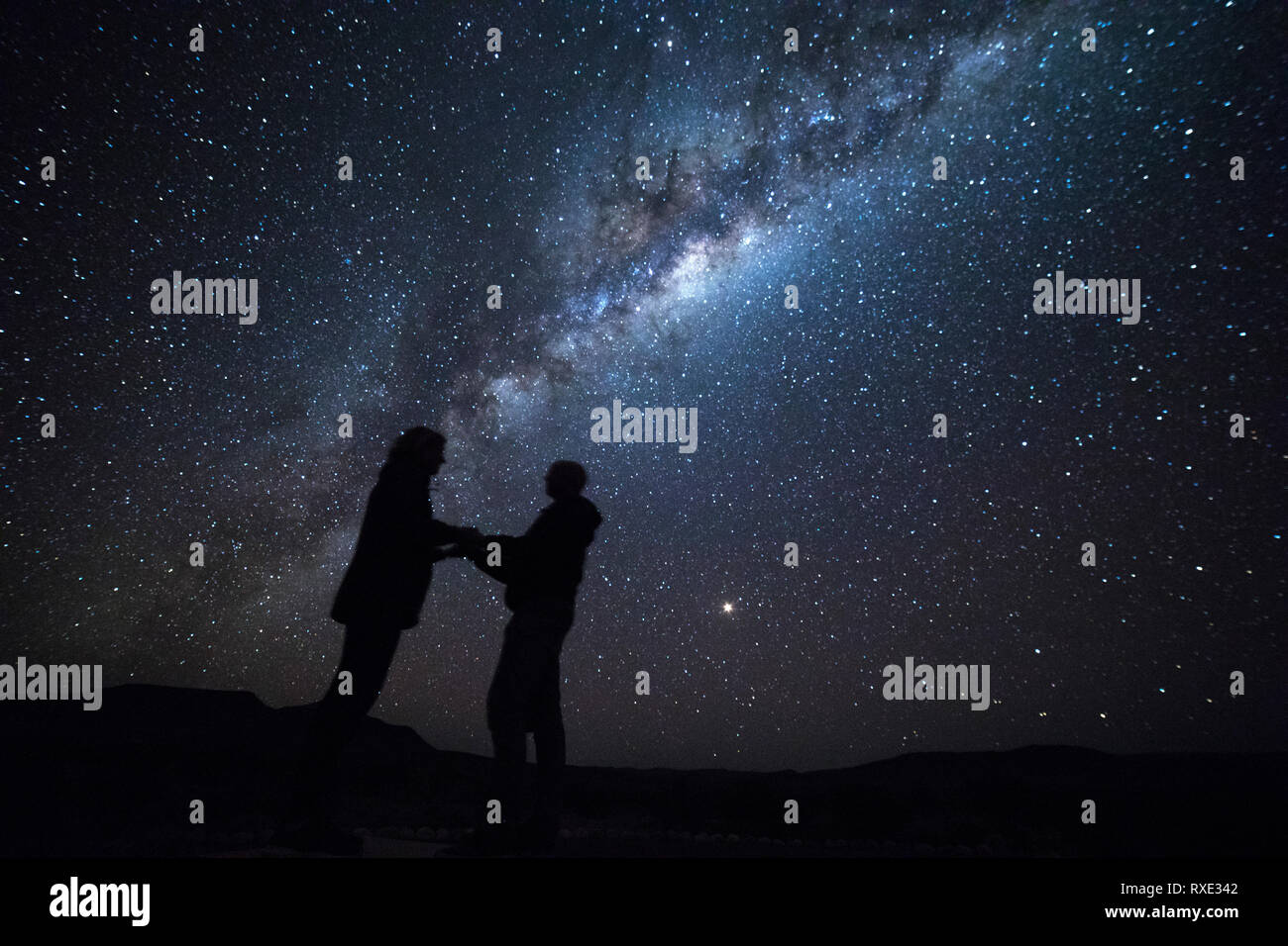 Ein Mann schlägt seine Freundin unter den Sternen der Milchstraße. Stockfoto