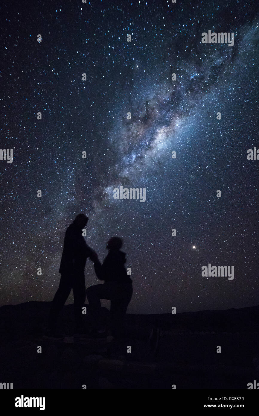 Ein Mann schlägt seine Freundin unter den Sternen der Milchstraße. Stockfoto