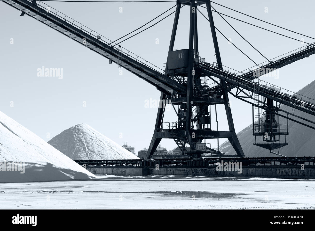 Weiße Berge Stapeln mit einem großen industriellen Maschinen auf Schienen. Schwarz und Weiß Foto Stockfoto