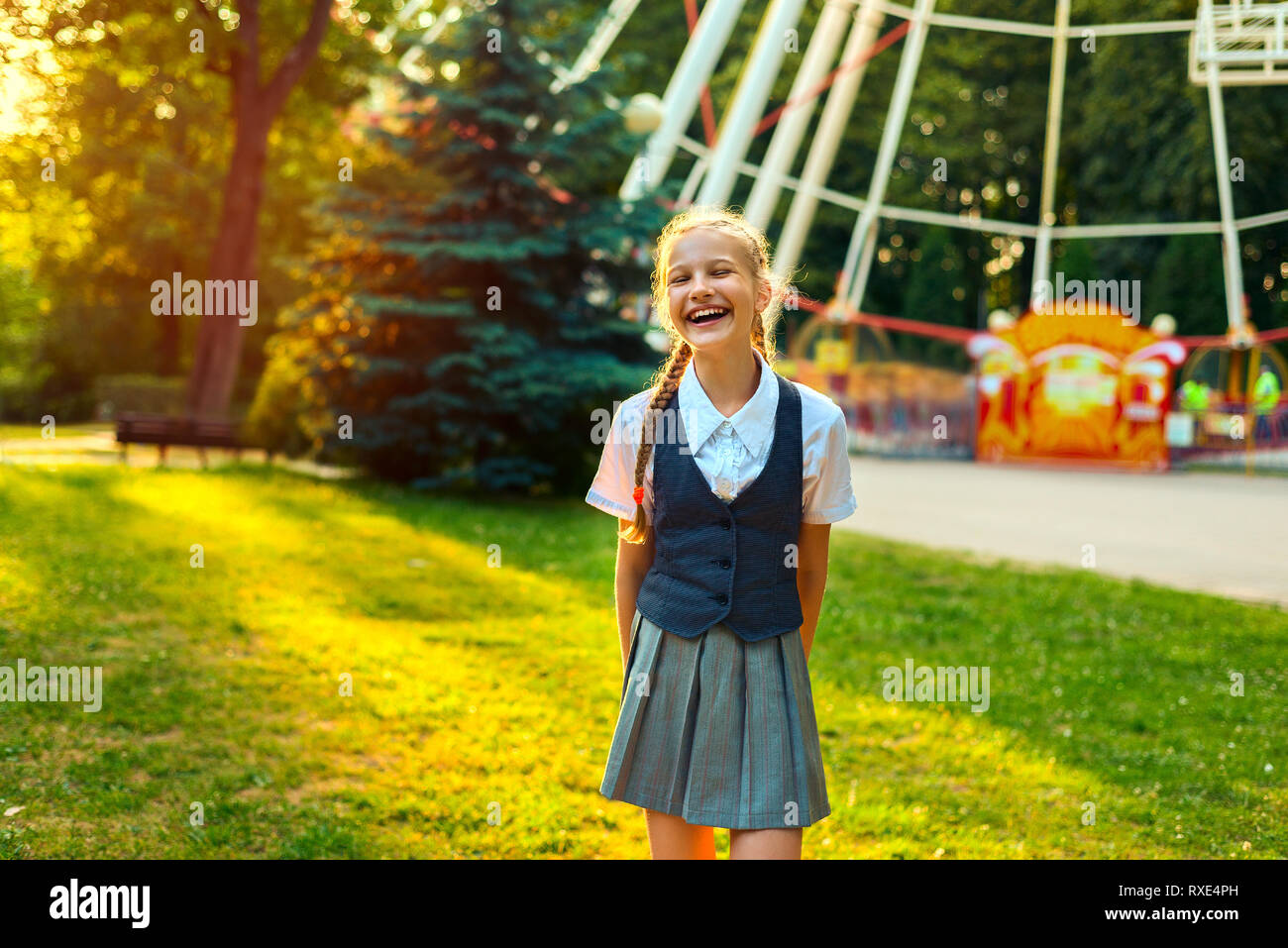 Portrait von Schulmädchen in Uniform lachen, lächeln und Spaß im Sommer im Park bei Sonnenuntergang im Sonnenlicht Stockfoto