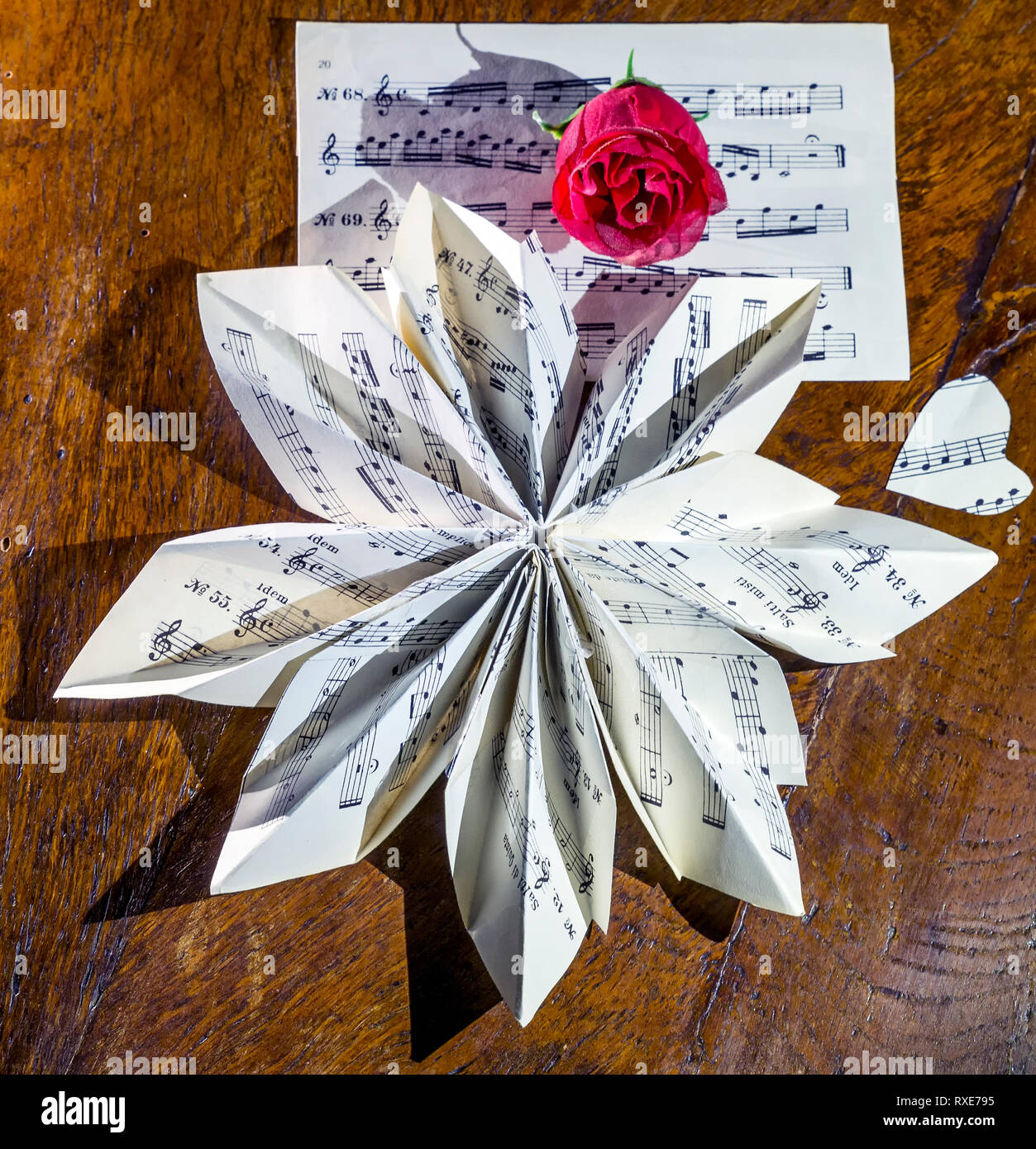 Noch immer leben Komposition mit einer Partitur in der Form einer Blüte gefaltet und eine rote Rose gemacht Stockfoto