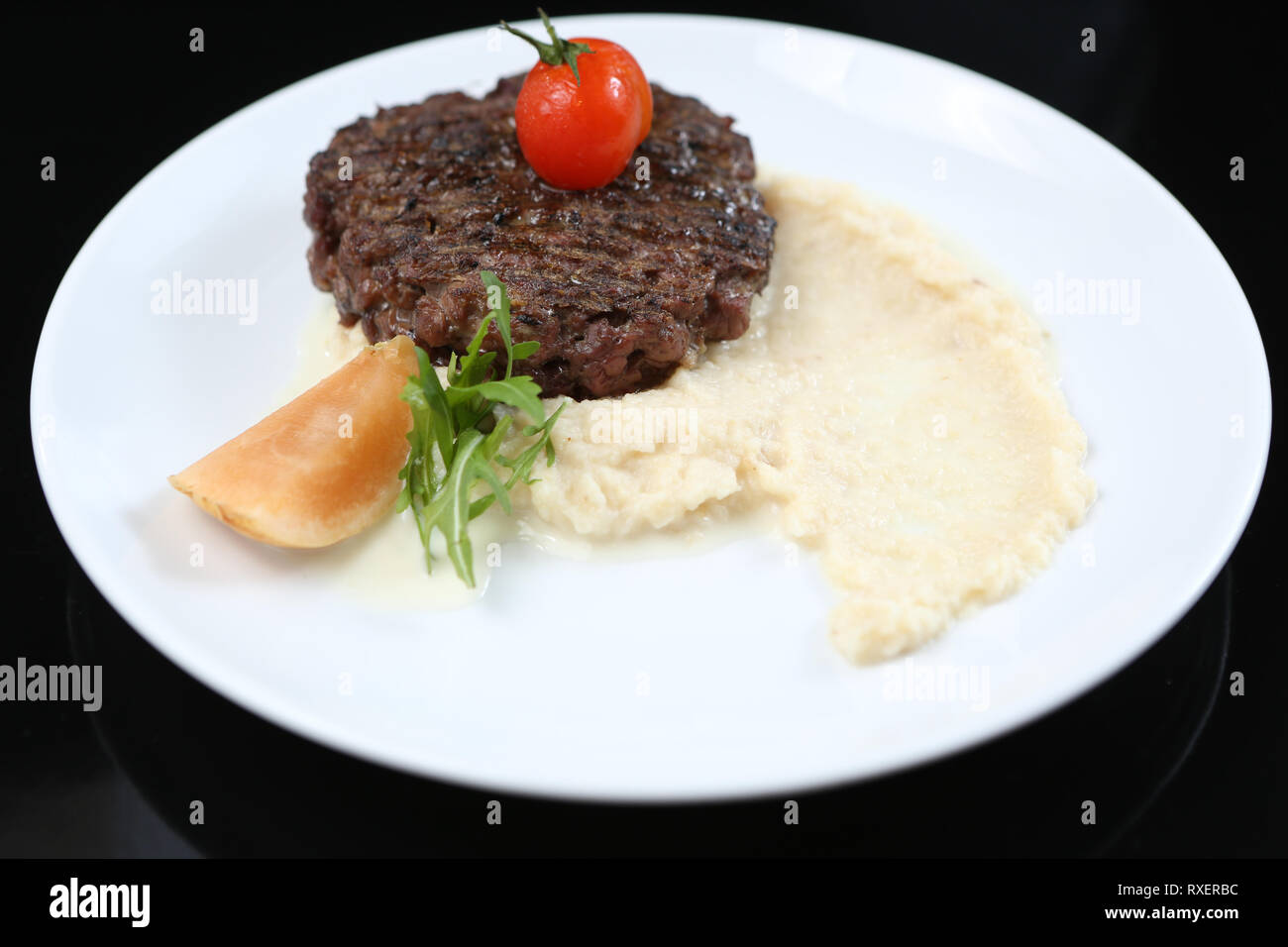 Gebratenes Fleisch Schnitzel auf dem Teller, mit Sellerie pürieren, garniert mit Tomaten Cherry und saure Äpfel, für ein Menü isoliert Stockfoto