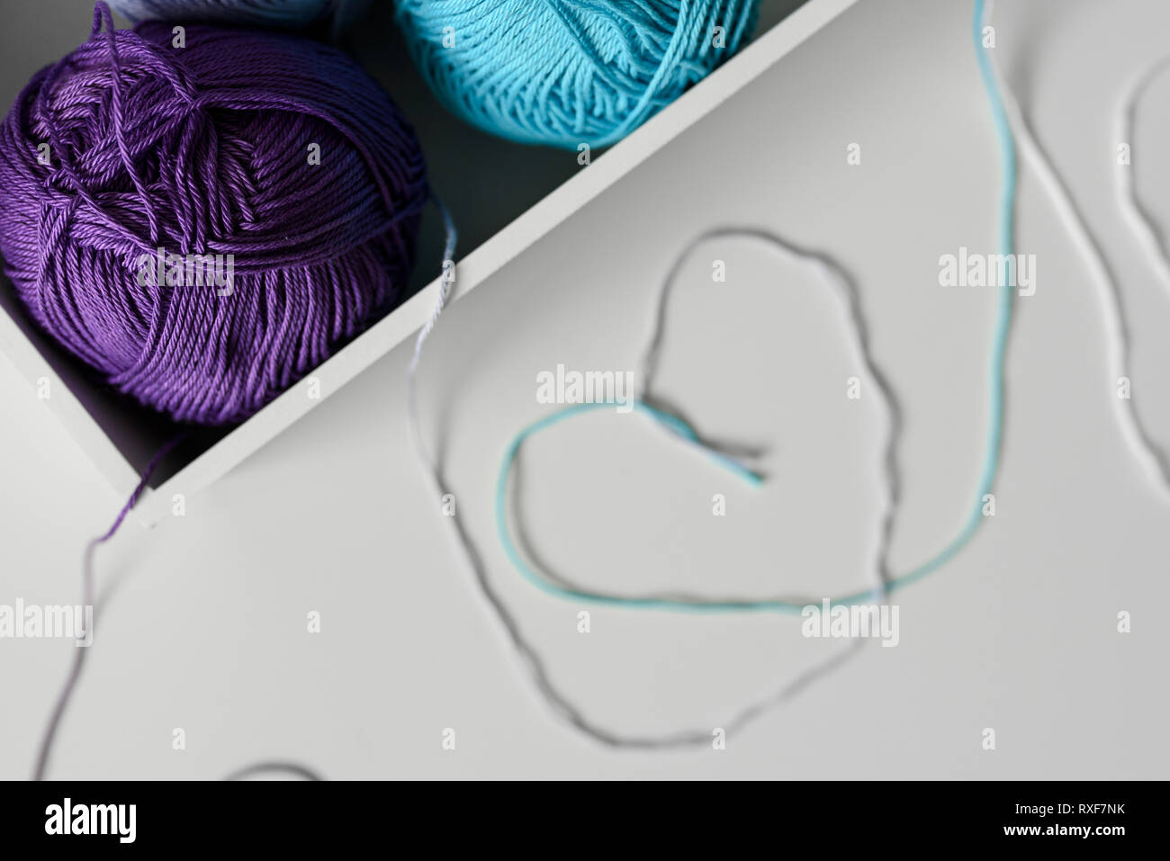 Hintergrund Kunst vom Gewinde der bunten Strickwolle Design als Herzen Symbole auf weißer Tisch. Fokus auf Garne Kugeln. Stockfoto