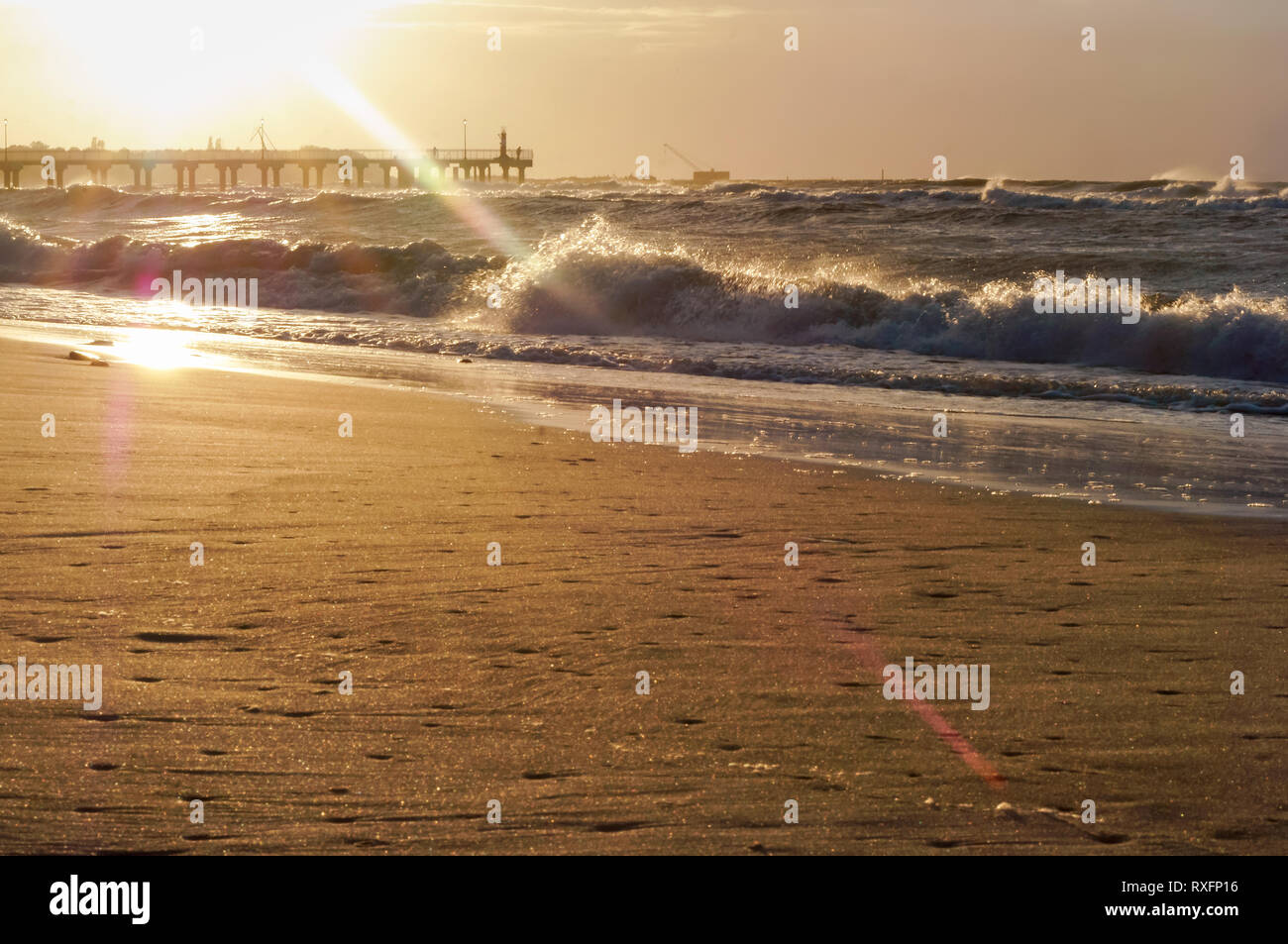 Sonnenuntergang über dem Meer. Reflexion des Sonnenlichts in den Meereswellen. Roter Himmel in den Strahlen des Sonnenuntergangs. Stockfoto