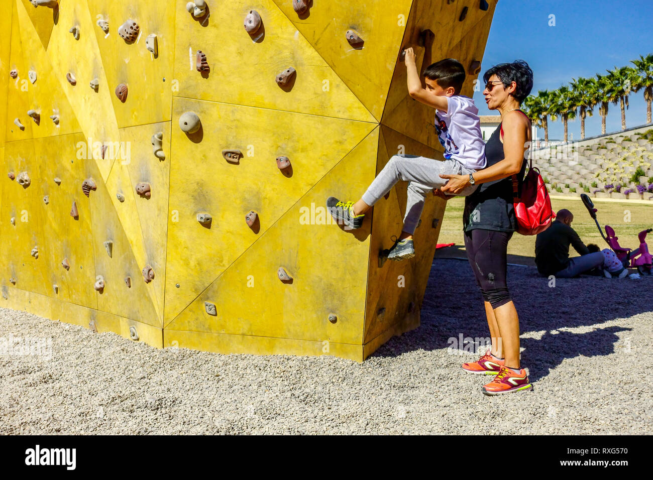 Valencia Central Park, die Mutter hilft dem Sohn an der Kletterwand, Kind Stockfoto