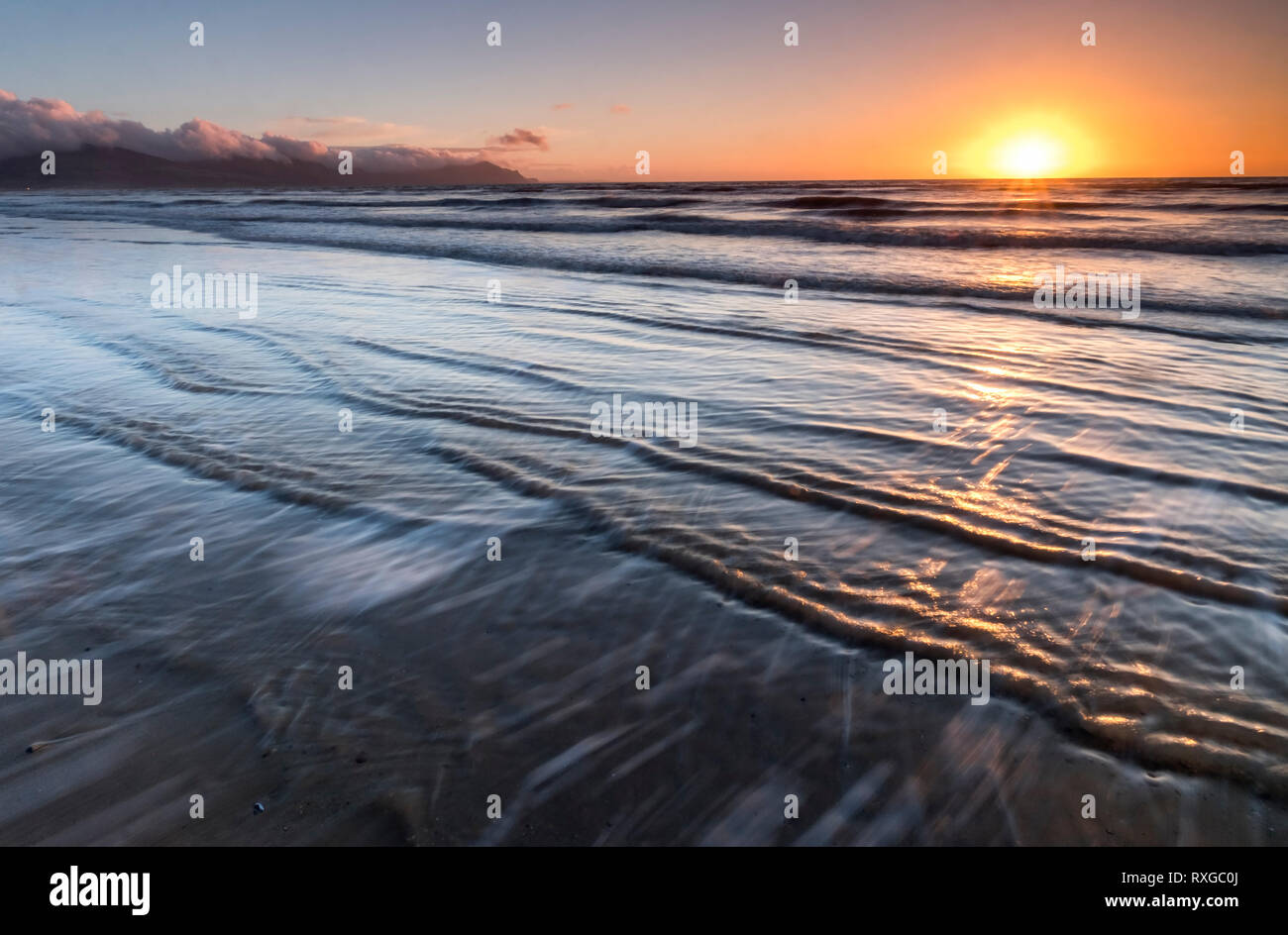 Dinas Dinlle Strand unterstützt durch die Halbinsel Lleyn bei Sonnenuntergang, Gwynedd, Wales, Großbritannien Stockfoto