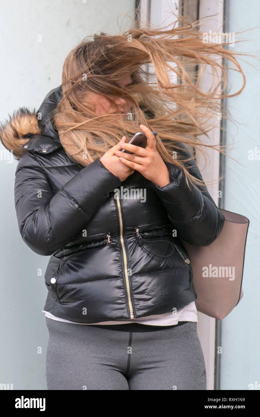 Blackpool, Großbritannien. 10. März, 2019. Strong gale force Winde an der Küste. Shopper sind windswept als der starke Stürmische Winde fegen durch die Innenstadt. Wetter Warnungen haben sich über den Nordwesten von England für schwere Böen und Starkregen über das Wochenende ausgestellt wurde. . Credit: MediaWorldImages/Alamy leben Nachrichten Stockfoto