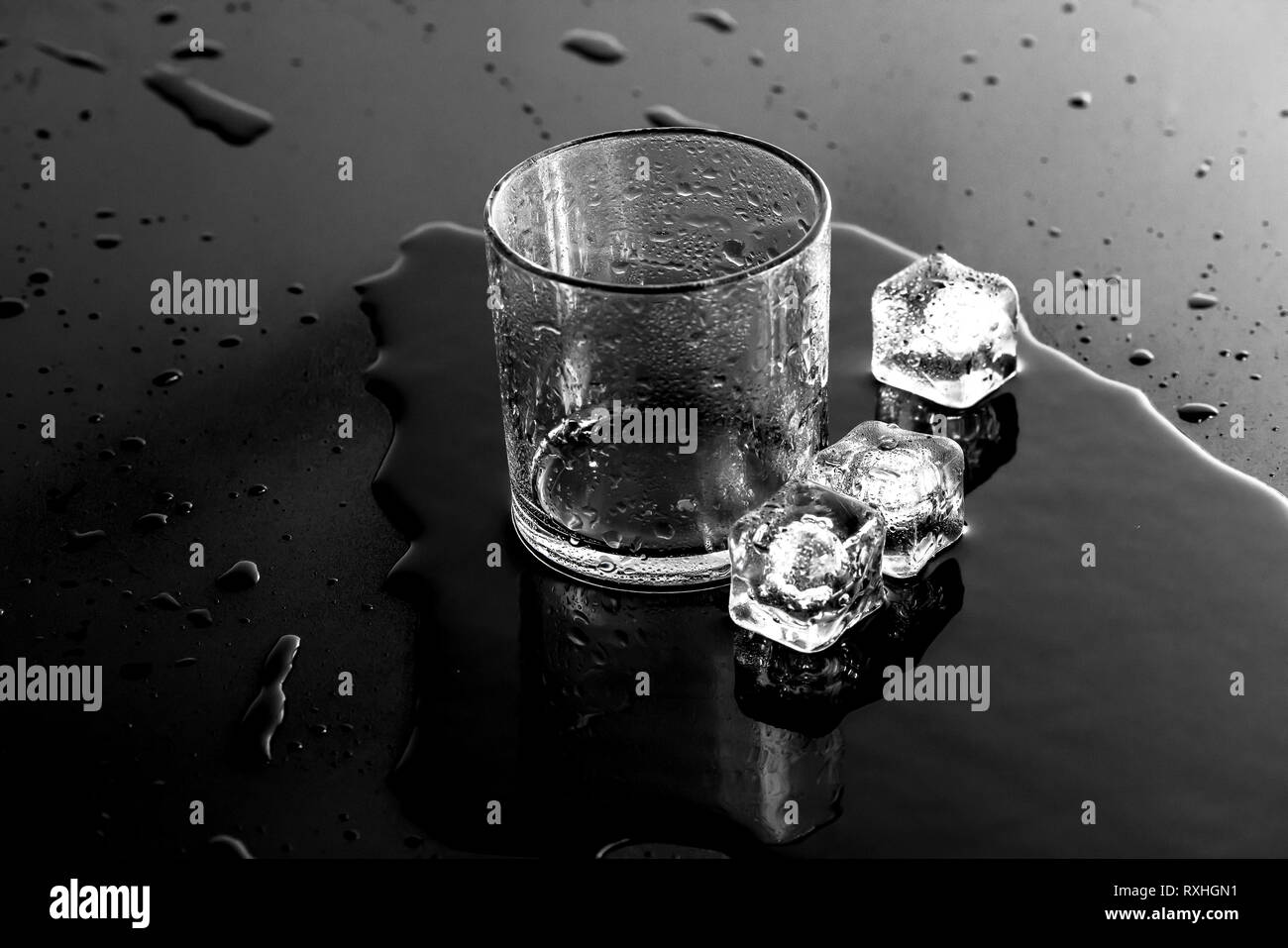 Glas mit Eiswürfeln auf einer nassen Oberfläche Stockfoto