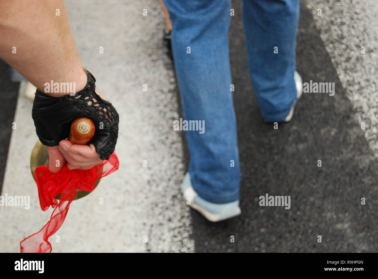 Politischer Protest, öffentliche Vorführung oder Streik in Stadt Straße. Aktivismus, der Zivilgesellschaft. Männliche Hand in schwarz Handschuh Holding eine Glocke, Beine Demonstrator. Stockfoto