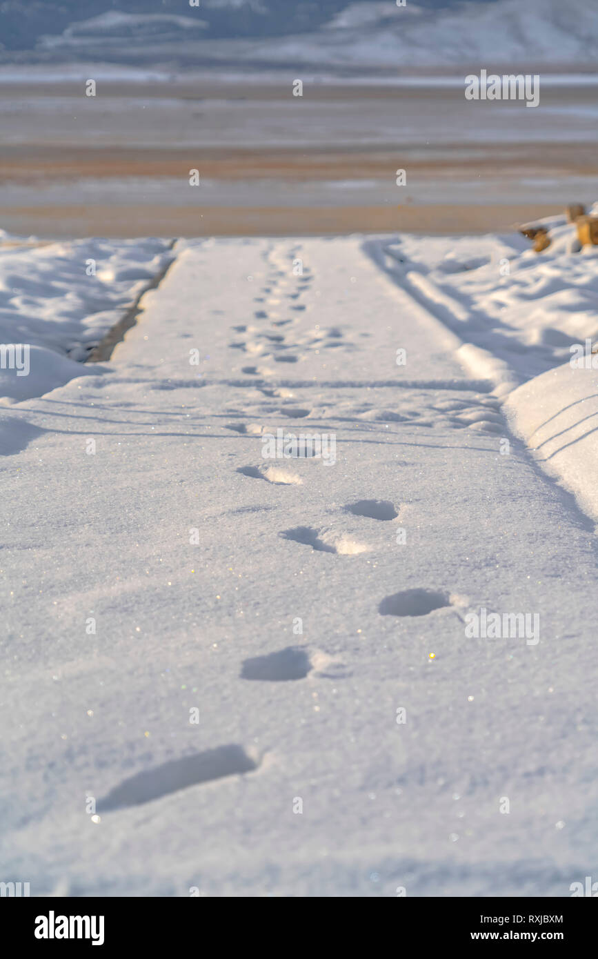Fußabdrücke auf dem glitzernden Schnee fallen weg Stockfoto